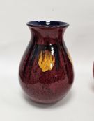 Poole pottery baluster vase with flared neck, decorated with probably the Exodus pattern on a red