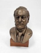 Bronzed fibreglass bust of a middle-aged man with sideburns and wearing a shirt and tie, held on a