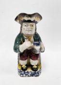 English Prattware Toby jug, circa 1820, modelled seated holding a jug and cup, wearing a sponged
