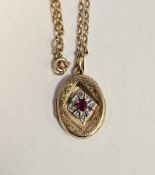 9ct yellow gold, ruby and diamond locket pendant, the front of the oval locket with engraved