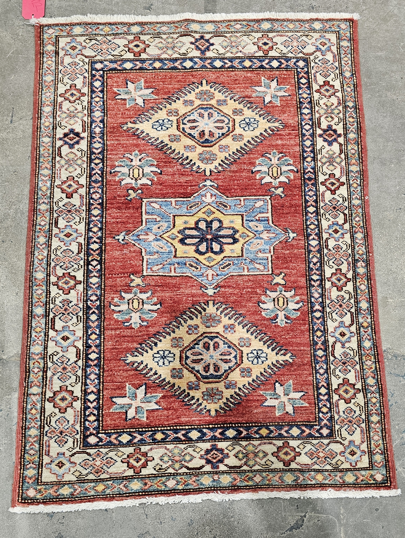 Two small Kazak rugs decorated with geometric patterns within a border, each 121cm x 81cm (2)
