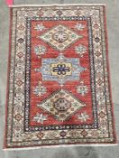 Two small Kazak rugs decorated with geometric patterns within a border, each 121cm x 81cm (2)