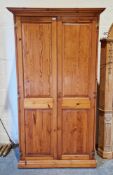 Modern pine wardrobe, the two panel doors opening to a shelf and a hanging rail, on plinth base (