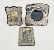 Three Victorian-style silver photograph frames, the largest embossed with two birds in flight