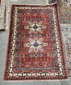 Kazak red ground rug with geometric motifs within a border, 179cm x 119cm