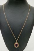 9ct yellow gold and purple stone oval pendant, the claw set faceted stone in a rope twist and open