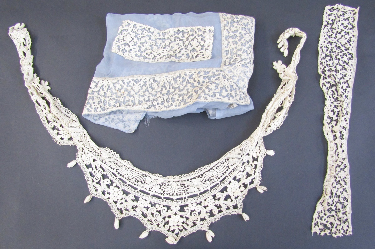 Quantity lengths of bobbin tape lace, scroll design including various lengths on blue chiffon