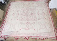 A mid twentieth century bedspread, cream with emblems embroidered in red, with deep fringe 248 m x
