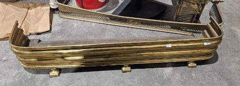 Two vintage brass fenders, one raised on three feet, the other of pierced design (2)