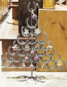 Large ornamental Christmas tree constructed from horseshoes and rebar, decorated with various