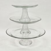 Three 20th century graduating glass cake stands or comports in sizes, each with upturned rim, on