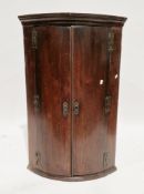 George III mahogany bowfronted hanging corner cupboard, the plain double doors opening to three