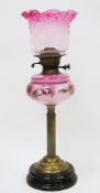 Victorian brass column oil lamp having a frilled pink tinted shade and opaque pink glass well