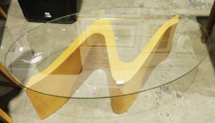 Tom Schneider Wave coffee table, the oval glass top on an S-scroll pale oak plinth base, 39cm high x