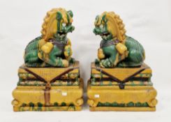 Pair of Chinese stoneware Sancai glazed buddhist lion dogs on bases, 20th century, each stylised dog