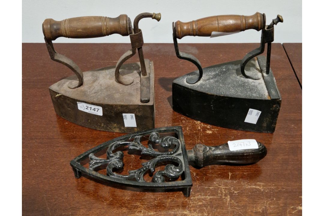 Two Victorian vintage irons with turned wooden handles and a pierced iron trivet (3)