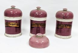 Set of three 19th century English pottery cylindrical apothecary jars and four domed covers, pink