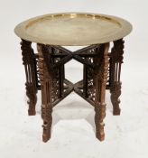 Early 20th century Indian folding table, the circular brass top with chased floral decoration, on