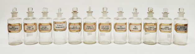 Twelve early 20th century 'label under glass' apothecary bottles, each of cylindrical form with