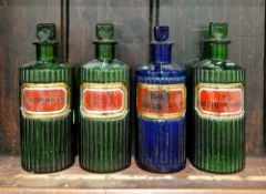 Three labelled and ribbed green glass poison bottles and stoppers and a blue example similar,