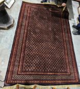 Afghan wool rug, 20th century, the central field with brown and orange edged rosettes on a dark blue