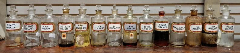 Fourteen small early 20th century 'label under glass' apothecary bottles and stoppers, each of
