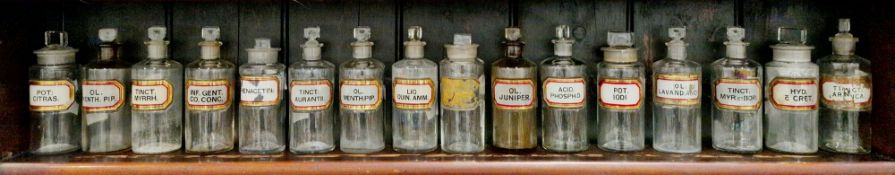 Sixteen various small early 20th century 'label under glass' apothecary bottles and stoppers, each