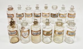 Fourteen early 20th century 'label under glass' apothecary bottles and 13 stoppers, each of