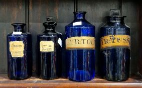 Four late 19th/early 20th century blue-tinted labelled apothecary bottles and two stoppers,