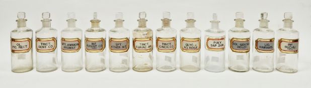 Twelve early 20th century 'label under glass' apothecary bottles, each of cylindrical form with