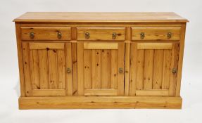 Modern pine dresser base with three frieze drawers and three cupboard doors, having brass drop