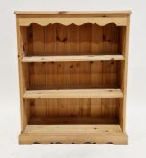Modern pine bookcase with carved shaped frieze, two adjustable shelves, on a plinth base, 91cm
