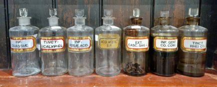 Seven early 20th century 'label under glass' apothecary bottles and stoppers, each of cylindrical