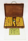 Mid-century South East Asian mahjong set comprising amber-coloured playing pieces and a directions