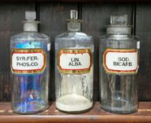Three large early 20th century 'label under glass' apothecary bottles and stoppers, each of
