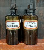 Two large early 20th century brown-tinted 'label under glass' apothecary bottles and stoppers,
