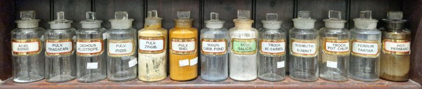 Thirteen early 20th century 'label under glass' apothecary bottles and stoppers, each of cylindrical