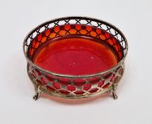 George V silver dish of circular form, pierced border, on four feet, cranberry glass liner,