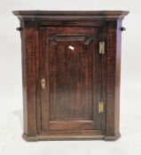 George III oak hanging corner cupboard, the single panel door opening to three shaped shelves,