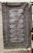 Persian Bokhara style greyish blue ground wool rug, decorated with a row of seven guls within a