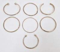 Three silver torque bangles, silver hinged bracelet with engraved decoration and three further