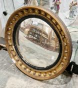 Regency style gilt convex wall mirror, the frame with moulded balls and ebonised rim, 64cm diameter