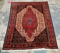 Persian Heriz type red ground wool rug, decorated with a central medallion and geometric stylised