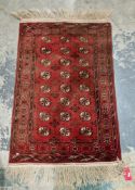Persian style Bokhara red ground wool rug, decorated with three rows of guls within a border, within