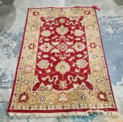 Cream and red ground rug, having a central panel decorated with flowers within a border, 183cm x