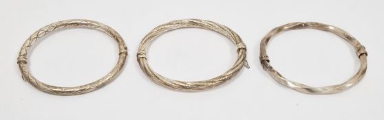 Three silver hallmarked hinged oval bangles, two of twisted design and the other with engraved