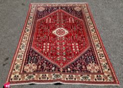 Iranian ' Persian Abade ' red ground wool rug, decorated with a central medallion and stylised