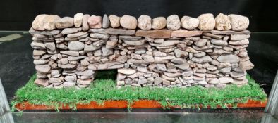 Hand-built model of a flint drystone wall, mounted on a faux grass covered base, 16cm high x 45cm