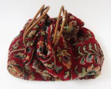 Carpet bag labelled Carpet Bags Suffolk England, with leather strap handles, patterned on a dark red