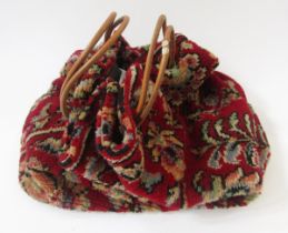 Carpet bag labelled Carpet Bags Suffolk England, with leather strap handles, patterned on a dark red